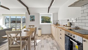 Eine moderne Küche mit Holzarbeitsplatten, einem eingebauten Backofen und einem Fenster mit Blick auf einen umzäunten Garten.