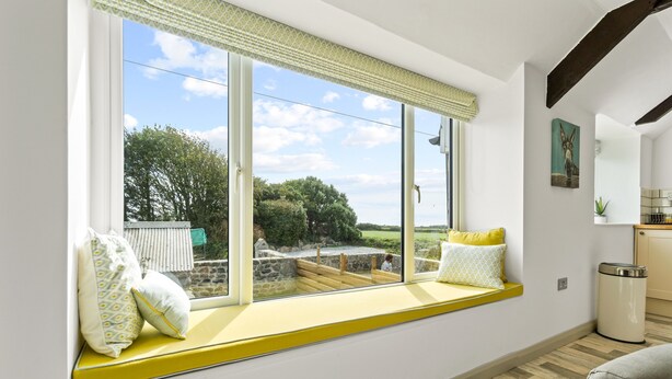 Ein Zimmer mit großem Fenster, einer integrierten Bank und Blick ins Freie.