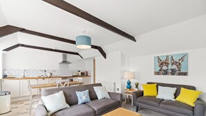 Ein modernes Wohnzimmer mit zwei Sofas, einem Couchtisch und einer Küche im Hintergrund.