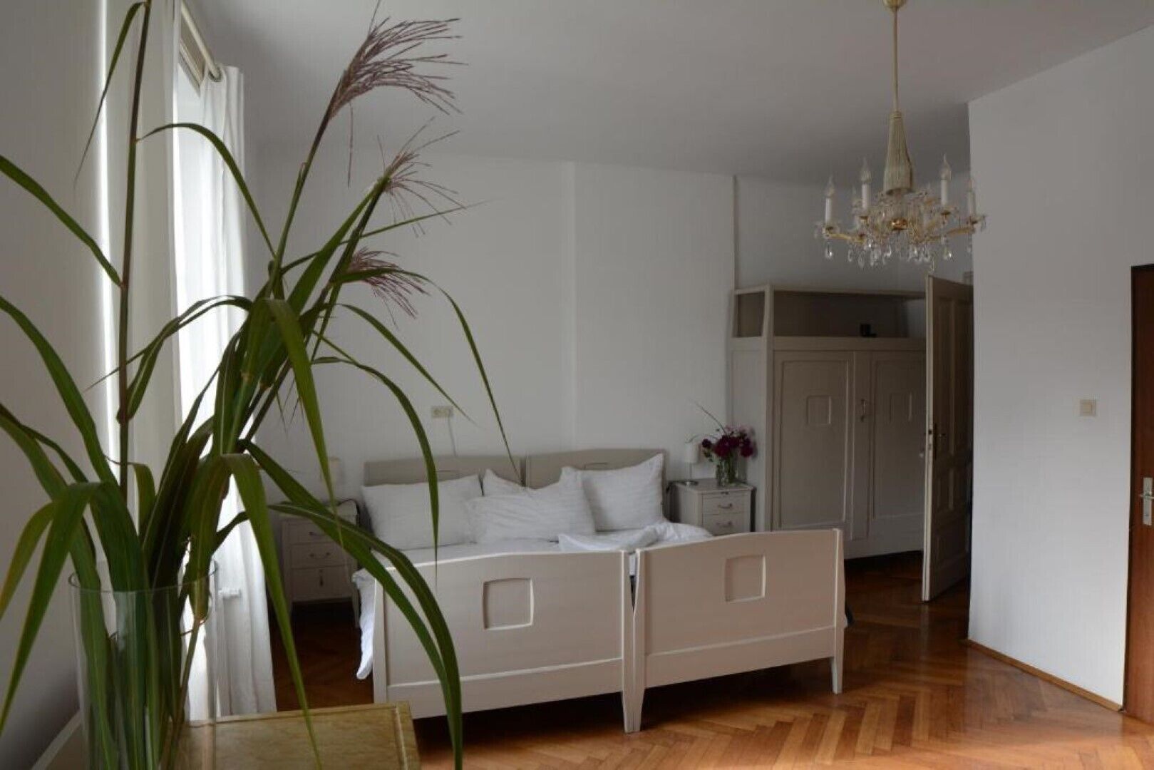 Un dormitorio con cama, mesita de noche y una planta en maceta.