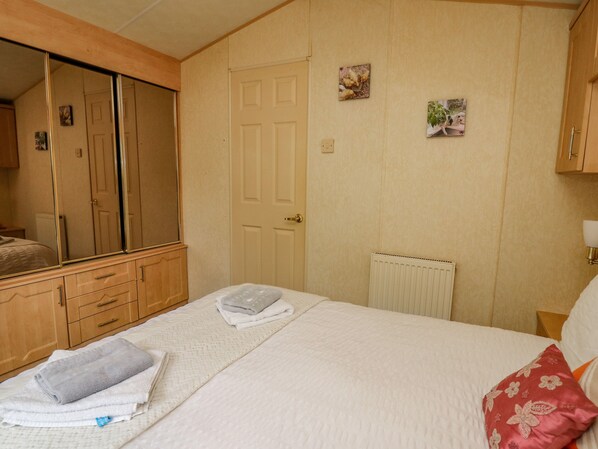 Une chambre à coucher avec un lit, un grand miroir, une armoire et un radiateur.