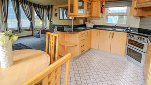 Een kleine keuken met houten kastjes, een wastafel en een fornuis.