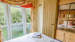 Een slaapkamer met een bed, een kledingkast, een deur en een raam met gordijnen.
