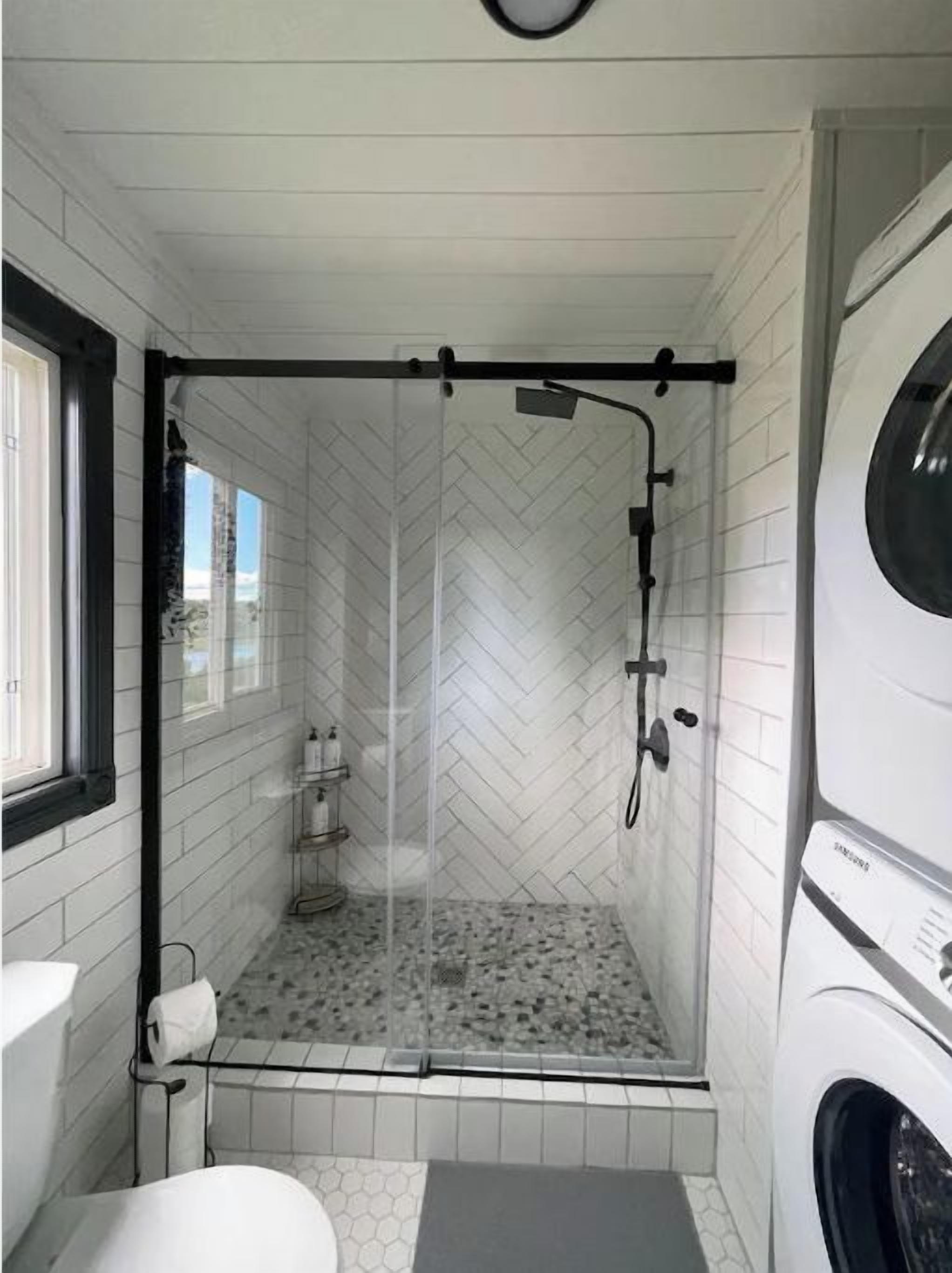 A compact bathroom with a shower, toilet, and washing machine.
