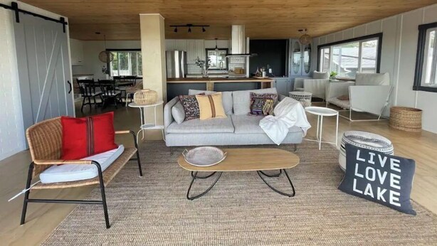 A modern living room with a sofa, coffee table, and a sign reading "LIVE LOVE LAKE".