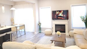 Un salon moderne avec une cheminée, un téléviseur et un coin repas.