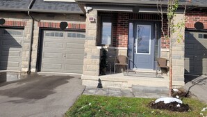 Il s’agit d’un immeuble résidentiel à deux étages, doté d’un garage, d’un petit porche avec une chaise et d’un arbre dans le jardin avant.