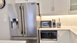 Une cuisine moderne équipée d’un réfrigérateur en acier inoxydable, d’un distributeur d’eau intégré, d’un four à micro-ondes et d’un grille-pain.