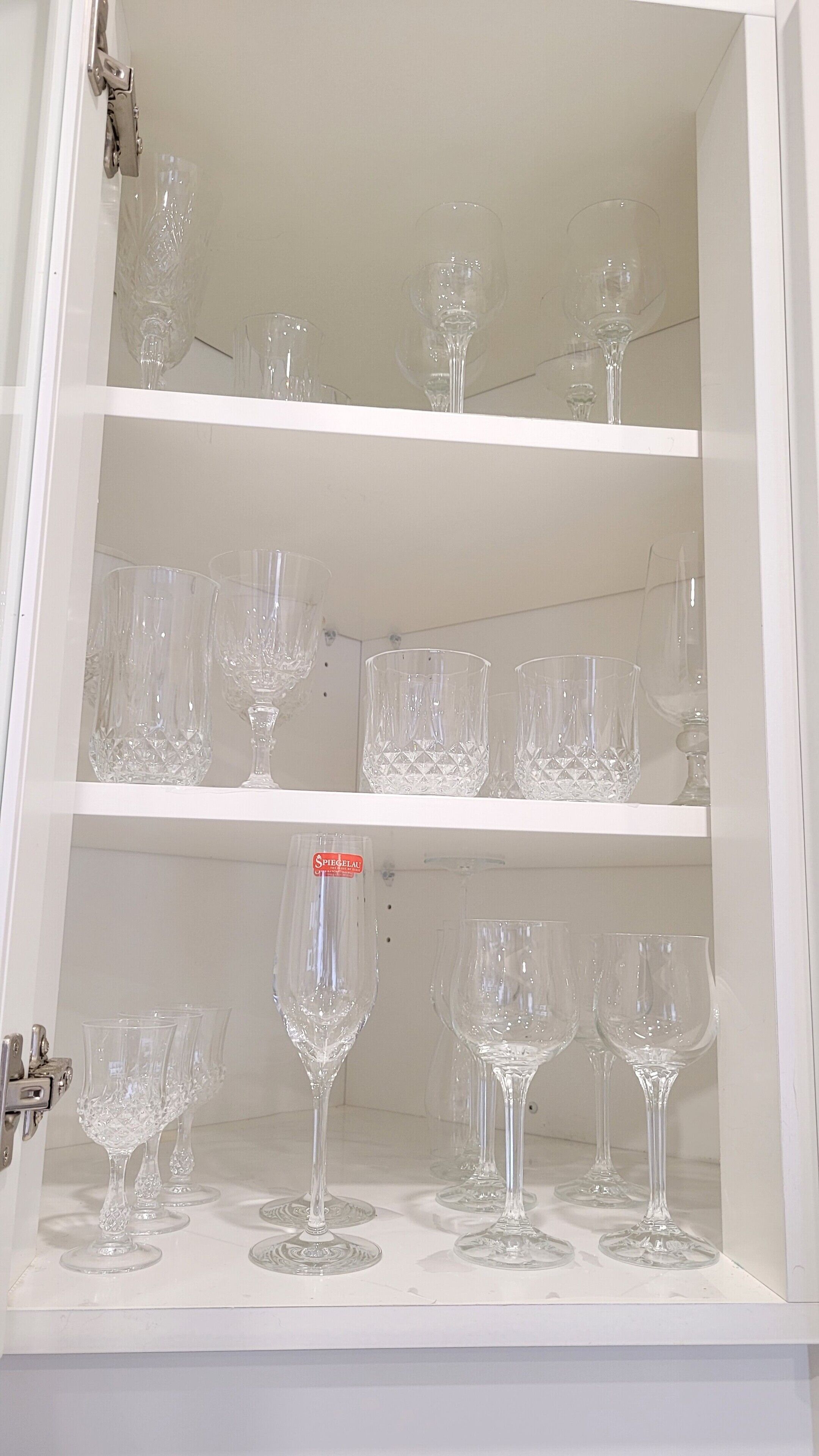 A cabinet with multiple shelves containing various clear glassware items.