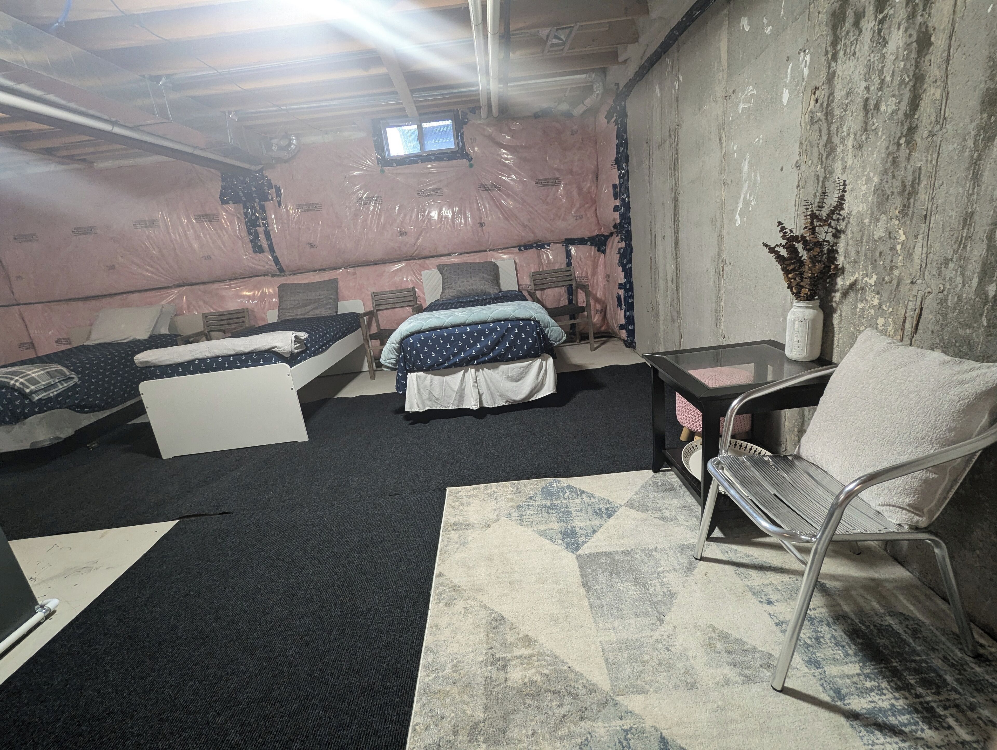 Une chambre avec deux lits, une petite table, une chaise et une fenêtre.
