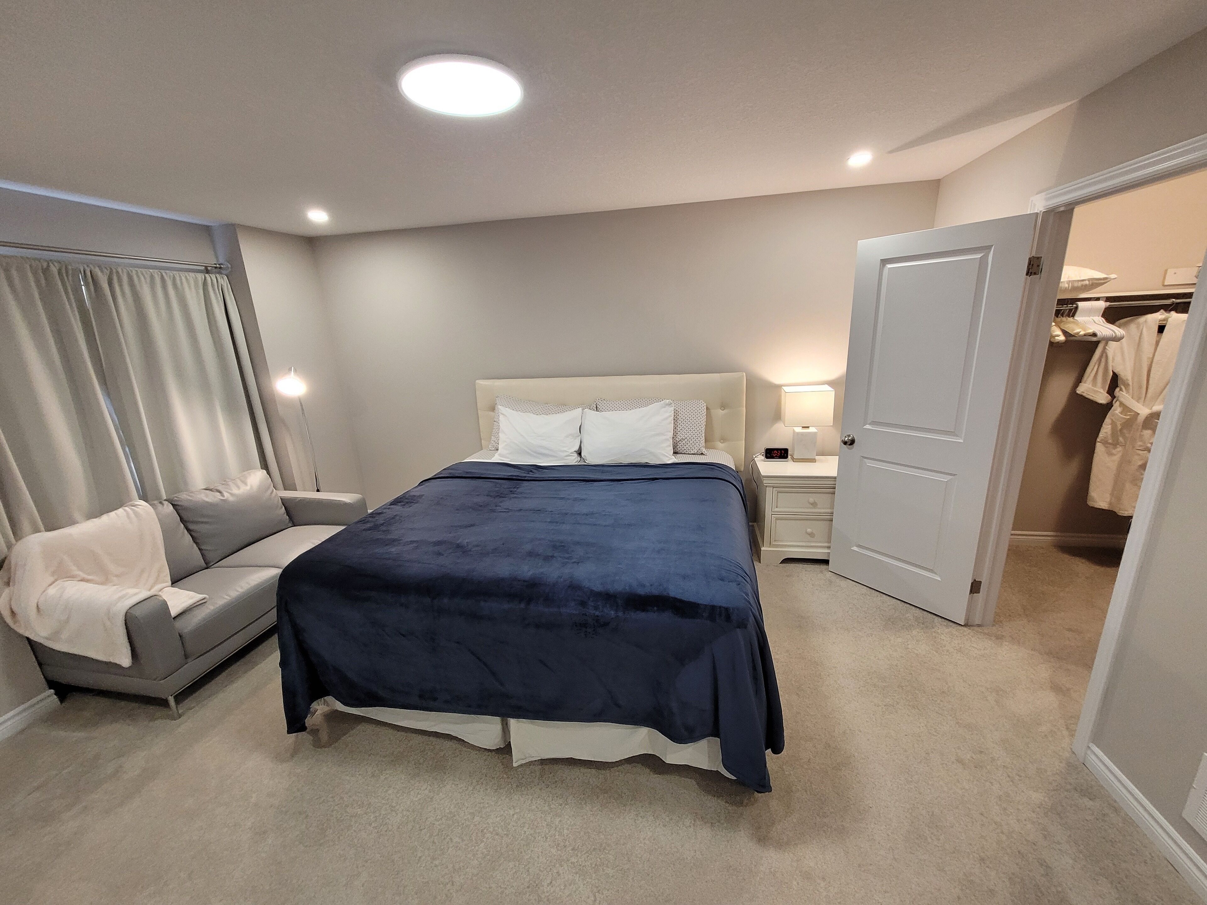 A bedroom with a bed, a nightstand, a lamp, a closet, and a door.