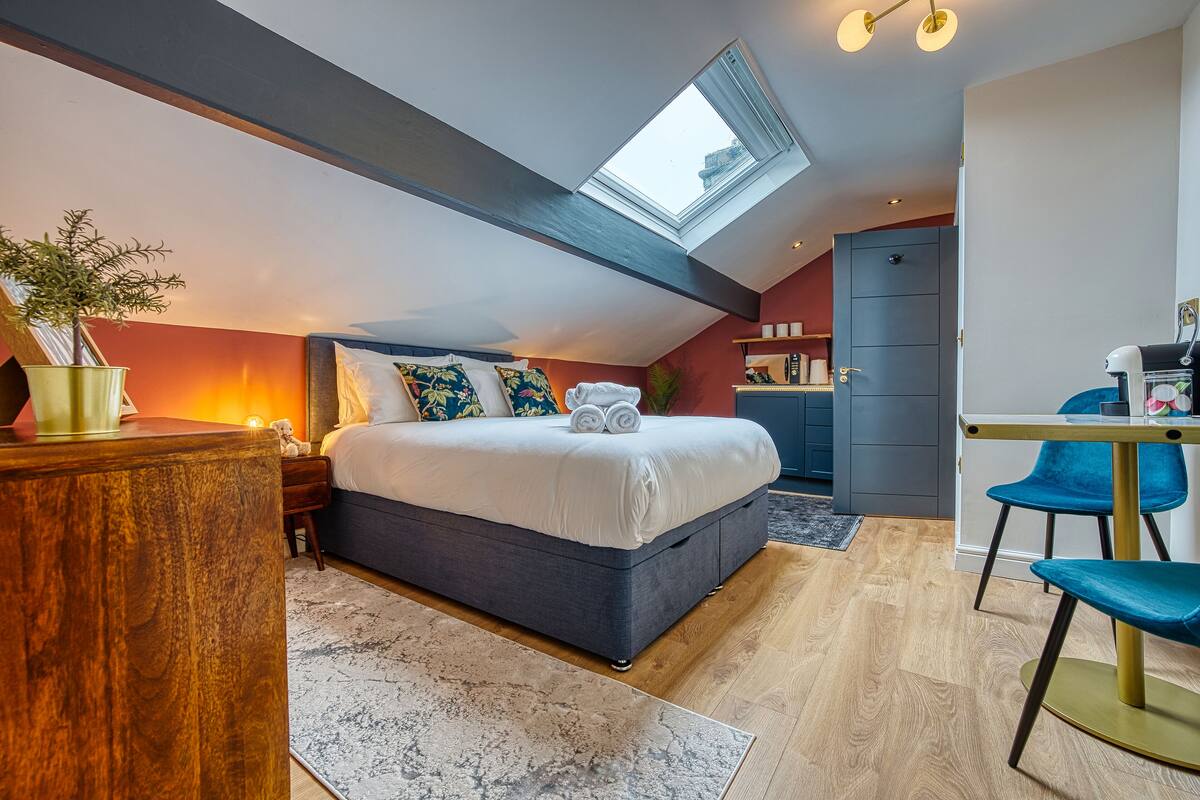 Un dormitorio moderno con tragaluz, una cama con toallas enrolladas, un escritorio y una silla.