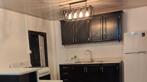A compact kitchen with dark cabinets, a white refrigerator, and a gas stove. - Apartment Luxe Next to Malls Central Location (Georgetown)