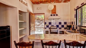 Una cocina con salpicadero de azulejos, estufa y pileta.