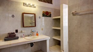 Un baño con lavamanos, espejo, toallero y zona de ducha.