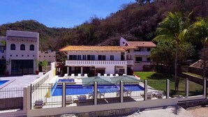 Un hotel con piscina, varios balcones y vistas a un paisaje montañoso.