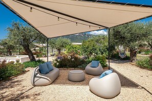 An outdoor seating area with a canopy, three bean bags, and a round table. - Locanda Della Meridiana - Cappero (Pula)