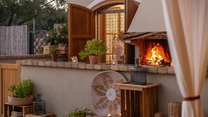 A cozy outdoor seating area with a fire pit, potted plants, and rustic wooden furniture. - Locanda Della Meridiana - Cappero (Pula)
