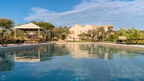 A swimming pool with a pavilion, a large building in the background, and surrounding greenery. - Locanda Della Meridiana - Olivo (Pula)