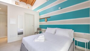 A hotel room with a bed, a chair, a small table, and a door. - Locanda Della Meridiana - Ginepro (Pula)