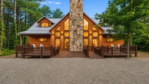 Une cabane en rondins avec une cheminée en pierre, une terrasse en bois et deux espaces de détente.