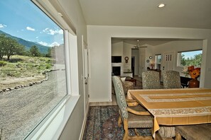 A dining area with a large window, a dining table, chairs, and a rug. - Challenger Views on Ridgecrest (Saguache County)