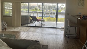 En stue med en stor skydedør, der fører ud til en balkon med jacuzzi og udsigt over en lysthavn.