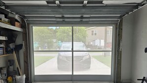 Uma garagem com um carro estacionado na frente, esteira e produtos de limpeza no interior.