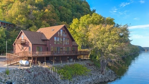 A cabin-style hotel with a large deck and a view of a river. - Water Street Lodge! Waterfront 4 Bedroom, 4 Bath, Sleeps 12! (Marquette)