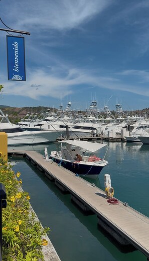 A marina with multiple boats docked, a clear sky, and a sign that reads 'bienvenido'.