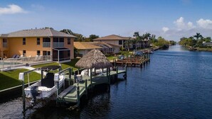A canal-side property with a dock, a thatched-roof structure, and a pool area. - Casa Laura Unit B - Lake Louise with a private pool (Cape Coral)