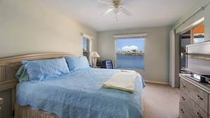 A bedroom with a bed, a ceiling fan, a TV, and a window with a view of the water. - Casa Laura Unit B - Lake Louise with a private pool (Cape Coral)