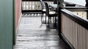 A wooden deck with a table and chairs, overlooking a lake and forested hills.