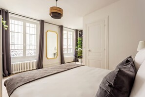 A bedroom with a large bed, a mirror, a radiator, and a window with curtains.