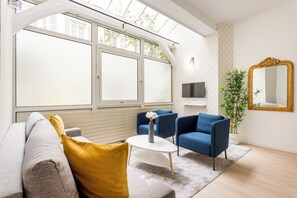 A modern living room with a sofa, two armchairs, a coffee table, a mirror, and a TV.