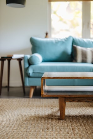 Una habitación con un sofá azul claro, una mesa de centro de madera y un tapete tejido.