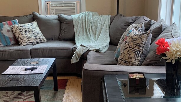 A living room with a sectional sofa, a coffee table, a floor lamp, and a window with blinds.