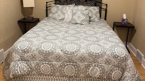 A neatly made bed with patterned bedding, a bedside lamp, and a tissue box on a nightstand.
