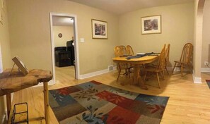 Enjoy meals in this dining area with a wooden table and six chairs, surrounded by framed artwork and a colorful rug.