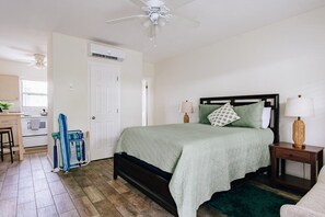 A bedroom with a bed, bedside tables, a ceiling fan, and a window.