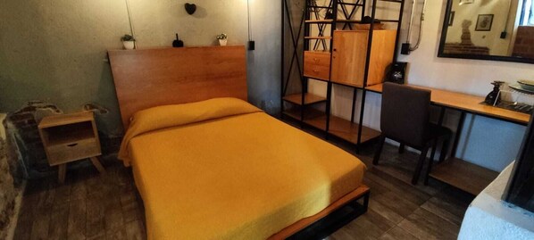 A compact room with a single bed, a small desk, and a chair.