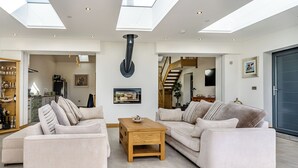 A spacious living area with two sofas, a coffee table, and a large window with skylights. - 3 bedroom accommodation in Pontyates (Pontyates)