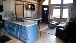 Una cocina amplia con una isla grande, un comedor con mesa y sillas, y una sala de estar con sofá.