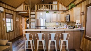 Una cocina acogedora con una isla central, armarios de madera y una pequeña zona de estar con cuatro sillas.