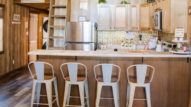Una cocina amplia con una isla central, techo de madera y un ventilador de techo.