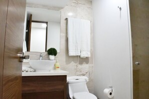 Une salle de bain avec un lavabo blanc, un miroir, des toilettes et une serviette accrochée au mur.