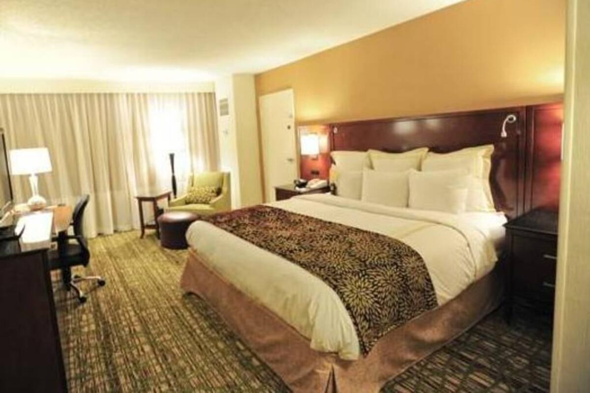 Une chambre d’hôtel avec un grand lit, un bureau, une chaise et une lampe.