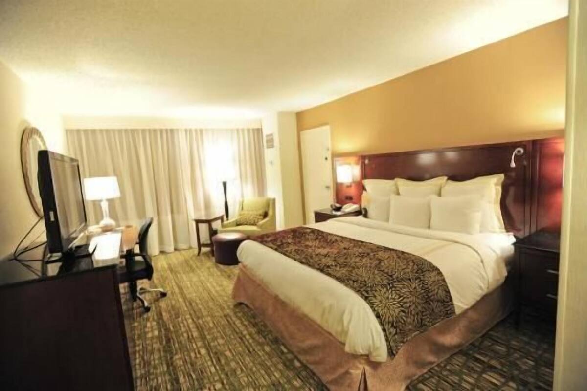 Une chambre d’hôtel équipée d’un lit, d’un bureau, d’une chaise, d’une lampe et d’un téléviseur.