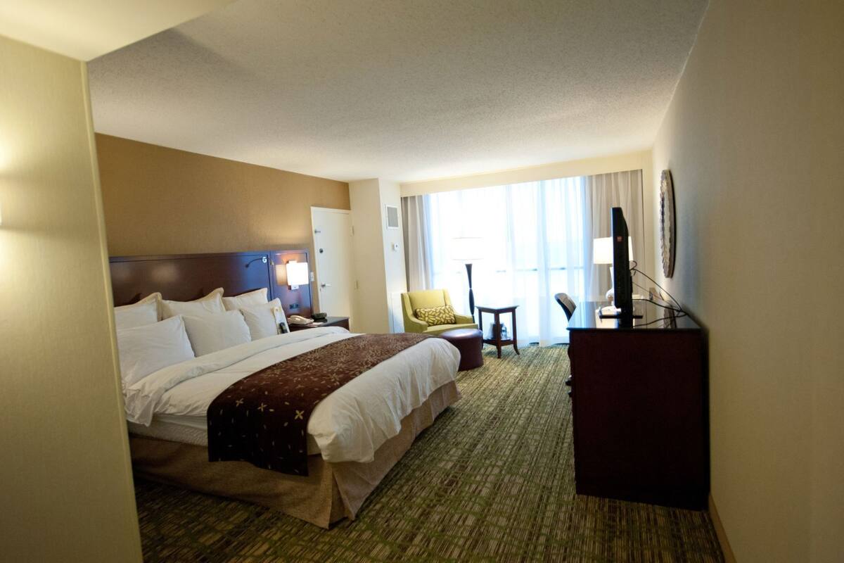 Une chambre d’hôtel avec un grand lit, un bureau, une chaise et un téléviseur.