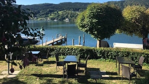 Seeblick mit Steg, Stühlen und Tischen für das Essen im Freien.